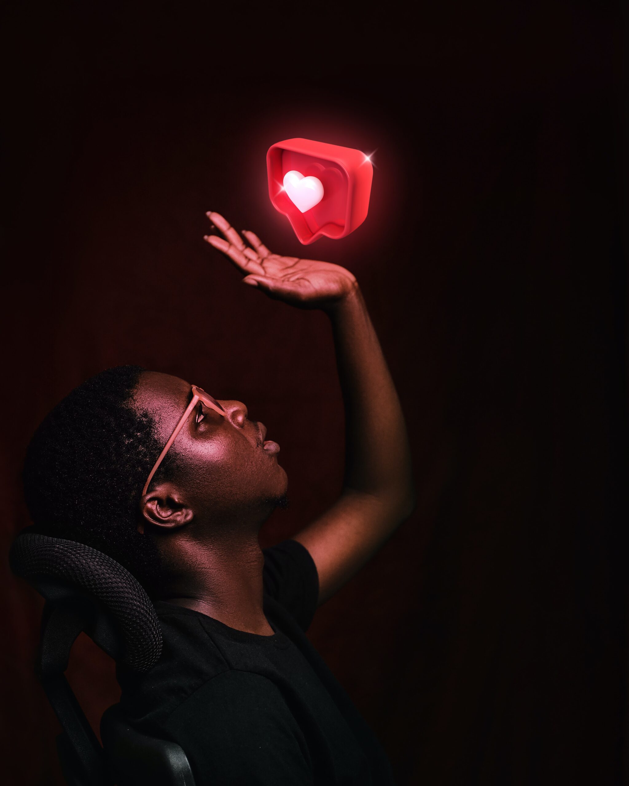 Man holding hand in the air and looking at an illuminated heart bubble hovering over his hand.