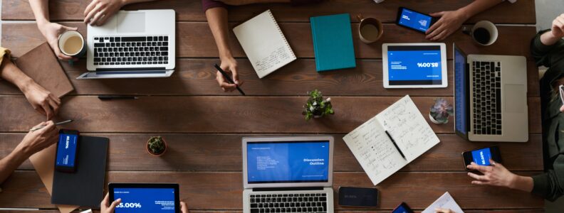 Overhead view of people working on their laptops around a table.